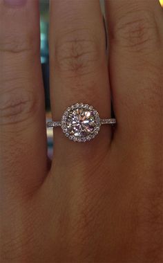 a woman's hand with a diamond ring on top of her finger and an engagement band