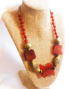 Tribal is composed of wonderfully large carnelian focal beads, especially the uniquely shaped center bead. It is accented with open woven brass Baule beads from Africa as well as the large round brass beads and Kenyan brass heishi beads. Red Agate Beaded Bohemian Necklace, Red Agate Bohemian Beaded Necklace, Bohemian Gold Carnelian Jewelry, Bohemian Gold Beads With Natural Stones, Bohemian Brass Beaded Necklaces With Natural Stones, Gold Beaded Necklaces With Natural Stones In Brass, Large Bronze Bohemian Beads, Bohemian Large Bronze Beads, Bohemian Brass Beads For Gifts