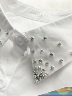 the collar of a white dress shirt with blue and silver jewels on it's lapel