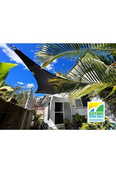 an umbrella is hanging from the side of a house with palm trees in front of it