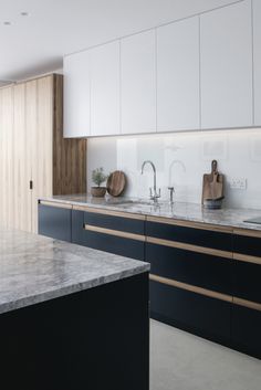 a modern kitchen with marble counter tops and wooden cabinetry, along with white cabinets