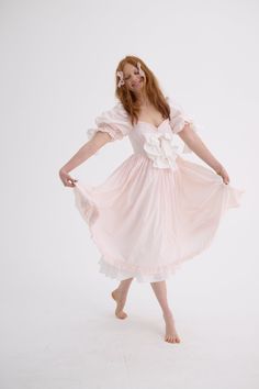 Look as delectable as a cherry blossom-infused macaron in the Confection Cottontail—a blush cotton midi-dress with puff sleeves and a pleated skirt. The contrasting bows and luscious ruffles harken back to a New Year’s celebration amid French aristocracy. Cotton midi-dress with puff sleeves and pleated skirt Contrast bows at bust and sleeves Ruffle detail at bust and hem Fully lined with cotton To ensure the best fit, measure your across bust and high waist before ordering and steam for optimal beauty. Sonnie is 5’11” and wearing a size L in Selkie. Her measurements are 39” bust, 30” waist, 40” hip. For more specifics, please text our help line. Fabric: 100% Paper Cotton Lining: 100% Cotton Care: Gently hand wash cold, lay flat to dry or dry clean Designed and fit in LA, Made in partnershi Silk Dressing Gown, Corset Skirt, Puff Dress, Cotton Midi Dress, Knitted Coat, Maxi Gowns, Party Girls, Sweater Accessories, Silk Dress