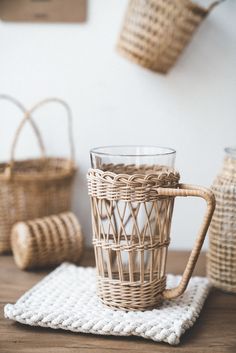 a wicker mug sitting on top of a wooden table next to two woven baskets