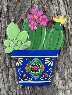 a cactus plant hanging from a tree with flowers on it's head and leaves in the pot