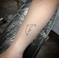 a person with a tattoo on their arm that has a dolphin's head in it