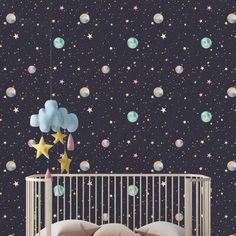 a baby's room with stars, clouds and planets on the wall behind a crib