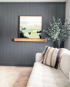 a living room with gray walls and white couches in front of a painting on the wall