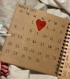 someone is holding a calendar with a heart on it