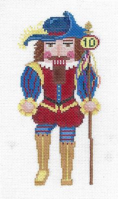 a cross stitch pattern of a nutcracker in red and blue uniform holding a sign