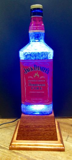 a bottle of alcohol sitting on top of a wooden table next to a blue light