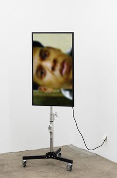 an image of a man's face is displayed on a flat screen tv stand