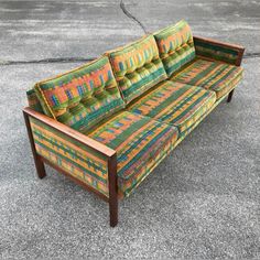 a colorful couch sitting on top of a cement floor next to a wooden frame and foot board