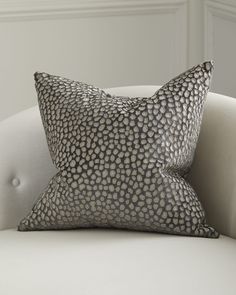 a white couch with a black and silver pillow on it's backrests