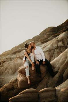 a man and woman sitting on top of a rock