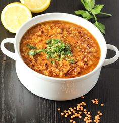 a white bowl filled with soup next to sliced lemons