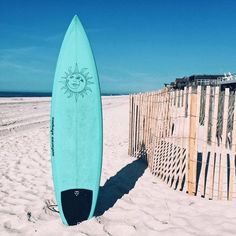 a surfboard leaning against a fence on the beach