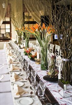 a long table with plates and vases filled with flowers