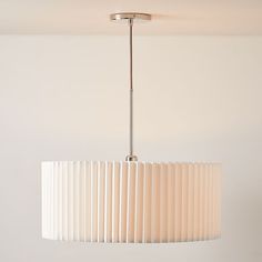 a white lamp hanging from a ceiling fixture in a room with no one around it