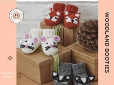 several knitted animal slippers are sitting on boxes with pine cones in the background