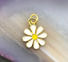 Enamel daisy charm.  18 kt. gold plated over brass. Sold individually.  MEASUREMENTS:  Approx. 5/8 inch (19mm) including the bail MATERIALS:  18kt gold plated over brass, enamel QUANTITY:  One Please message me with any questions. Thank you for looking and have a great day! Yellow Gold Enamel Jewelry With Flower Charm, Dainty Flower-shaped Enamel Jewelry, Dainty Gold Flower Charm, Gold Flower-shaped Enamel Jewelry, Gold Enamel Flower Jewelry, Yellow Gold Plated Flower-shaped Jewelry, White Dainty Pendant Charm, Gold Flower Charm For Gift, Dainty Yellow Flower Shaped Jewelry