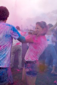 two people dancing with colored powder in the air