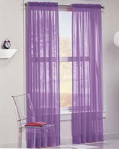 purple sheer curtains are hanging in front of a window with a clock on the wall