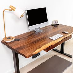 a wooden desk with a computer monitor and keyboard on it next to a mouse pad