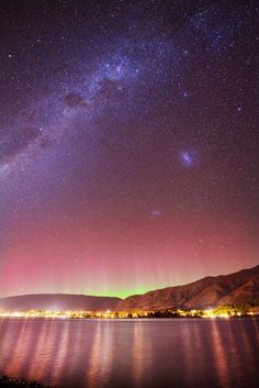 the night sky is filled with stars and bright lights as seen from across the water