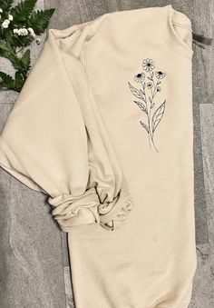 Welcome to Calvin's Street. You will love this long stem flower embroidered sweatshirt.  EMBROIDERY DESIGN   All designs are made with direct embroidery.  Design is embroidered on the left of the front chest.  SWEATSHIRT INFO 7.5 oz., 60/40 cotton/polyester Lined with fleece Unisex sizing SIZING Please look at the sizing chart in my product photos for measurements. If the size you need is sold out message me so I can check to see if my supplier offers/has your size! EMBROIDERY THREAD CARE 1. For best results, wash in warm water with a mild detergent. 2. Do not add bleaching agents such as chlorine, peroxide or sodium carbonate. 3. Do not line dry. Garments should be tumble dried at warm setting. 4. Never leave damp or wet embroidered articles folded or stuck together. 5. Never wring out an Embroidered Long Sleeve Sweatshirt For Spring, Spring Embroidered Long Sleeve Sweatshirt, Fall Cotton Sweatshirt With Floral Embroidery, Spring Long Sleeve Sweatshirt With Floral Embroidery, Spring Floral Embroidery Long Sleeve Sweatshirt, Spring Floral Embroidered Long Sleeve Sweatshirt, Spring Crew Neck Sweatshirt With Custom Embroidery, Spring Long Sleeve Tops With Custom Embroidery, Spring Sweatshirt With Custom Embroidery And Relaxed Fit