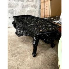 an ornate black coffee table sitting on top of a floor next to a brick wall