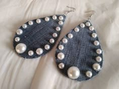 two pairs of denim and pearl earrings on a white bed with the fabric in the background