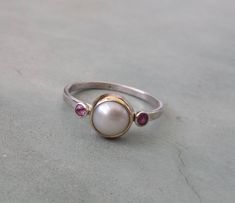 Pearl engagement ring,unique one of a kind pearl engagement ring,14k gold and sterling silver engagement ring,alternative engagement ring,pearl ring. One of a kind pearl engagement ring A beautiful fresh water pearl is set in a 14k solid yellow gold bezel on a delicate sterling silver band.a pink tourmaline is set on each side of the pearl. Genuine gemstones! Ring size is 7 u.s READY TO SHIP:) Measures: pearl diameter- 8mm tourmalines- 2 mm ring band- 1.5 mm Unique Pearl Jewelry For Anniversary, Elegant Hand Forged Round Ruby Ring, Unique Sterling Silver Pearl Promise Ring, Sterling Silver Pearl Ring For Wedding, Fine Jewelry, Sterling Silver Pearl Ring For Wedding, Sterling Silver Pearl Drop Ring, Elegant Hand Forged Ruby Ring For Anniversary, White Gold Sterling Silver Rings With Pearl Drop, Unique Sterling Silver Pearl Ring For Wedding