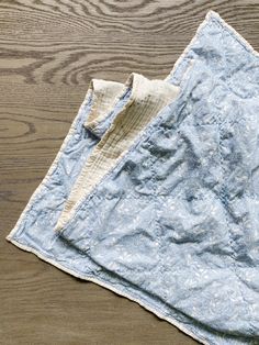 a blue and white blanket laying on top of a wooden floor next to a pair of scissors