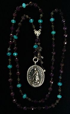 Now available in Sterling Silver, the Christo Rey in Amethyst is a rosary inspired necklace made with five decades and illumination beads of labradorite and crysoprase for special intentions to mark the Padre Beads. A double sided holy medal features Saint Michael the Archangel and Our Lady of Guadalupe made in Sterling Silver. The original medal dates back to 1682 when it was cast as a token of gratitude to be given to the generous patrons who helped build the "Templo Expiatorio a Cristo Rey" - Spiritual Crucifix Gemstone Jewelry, Spiritual Healing Jewelry With Miraculous Medal, Spiritual Purple Jewelry With Unique Variations, Handmade Spiritual Crucifix Necklaces, Handmade Spiritual Crucifix Necklace, Spiritual Oval Necklace With Gemstone Accents, Rosary Inspired Necklace, Saint Michael The Archangel, Michael The Archangel