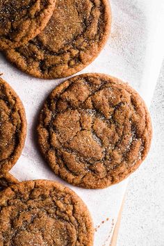 four chocolate cookies sitting on top of a piece of paper next to a wooden spoon