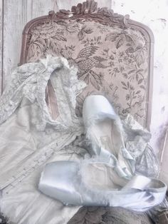 an old chair with some white cloth on it and a ballerina's shoes