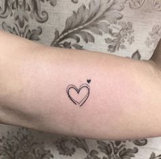 a small heart tattoo on the arm