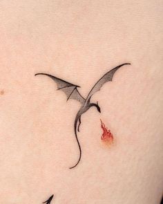 a small tattoo on the back of a woman's shoulder with a dragon flying over it