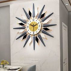 a clock that is on the side of a wall near a table with chairs and a vase