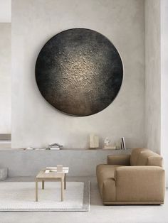 a living room filled with furniture and a round metal wall art hanging on the wall