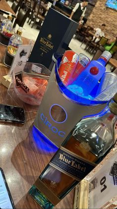 a table topped with bottles of alcohol and cell phones next to each other on top of a wooden table