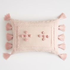 a pink pillow with tassels and pom - poms on the front