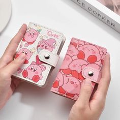 two women holding pink pig wallets on top of a white table next to each other