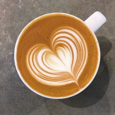 there is a cup of coffee with a heart in the foamy liquid on it