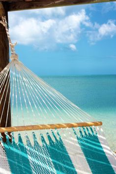 a hammock hanging from the side of a wooden structure over looking an ocean