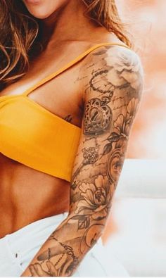 a woman with tattoos on her arm and chest is posing for the camera while wearing a yellow crop top