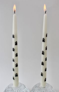 two white candles with black paw prints on them