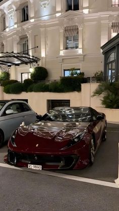 two sports cars parked in front of a hotel at night with the lights on,