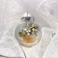 a glass vase with flowers inside on a white cloth