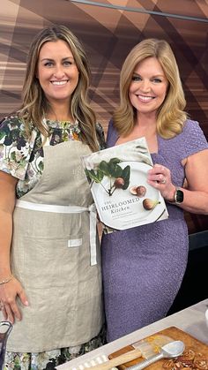 two women standing next to each other in front of food